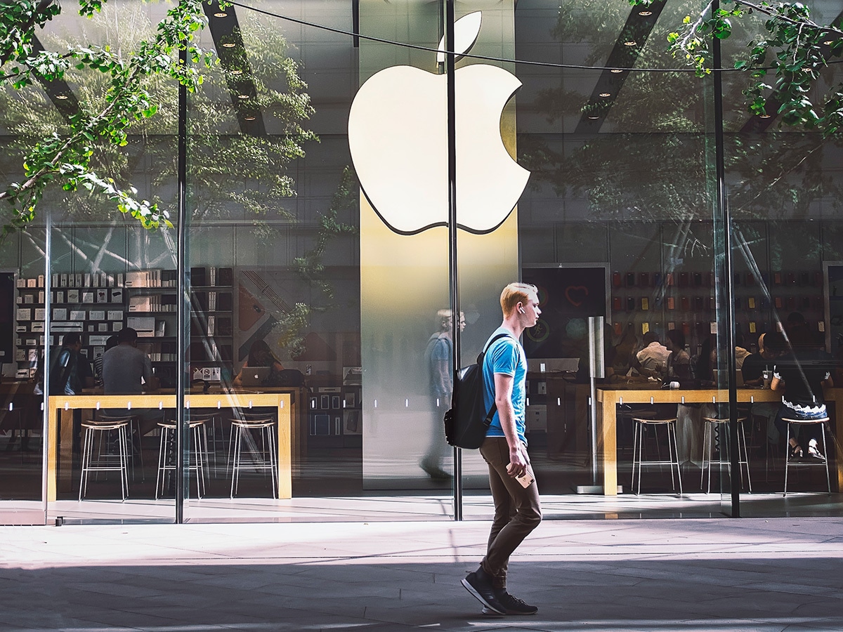 man walking in front of apple technology store