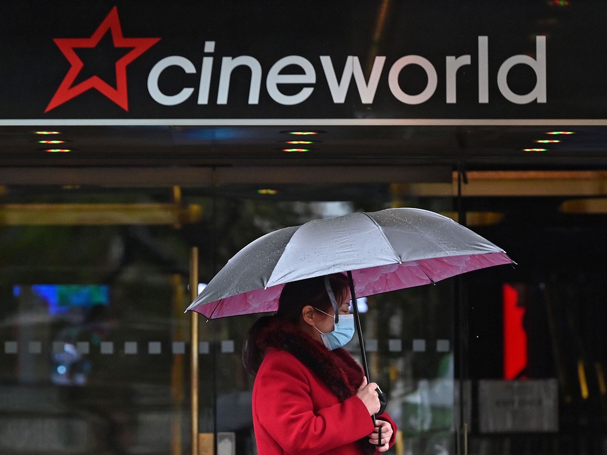 A woman with an umbrella outside a Cineworld theatre