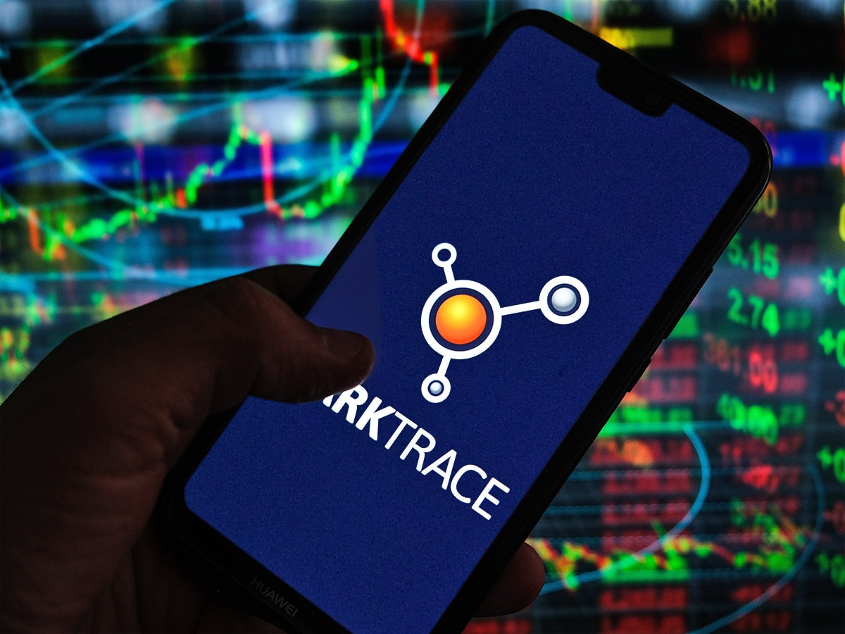 Darktrace share price: a hand holds a mobile phone displaying a Darktrace logo.