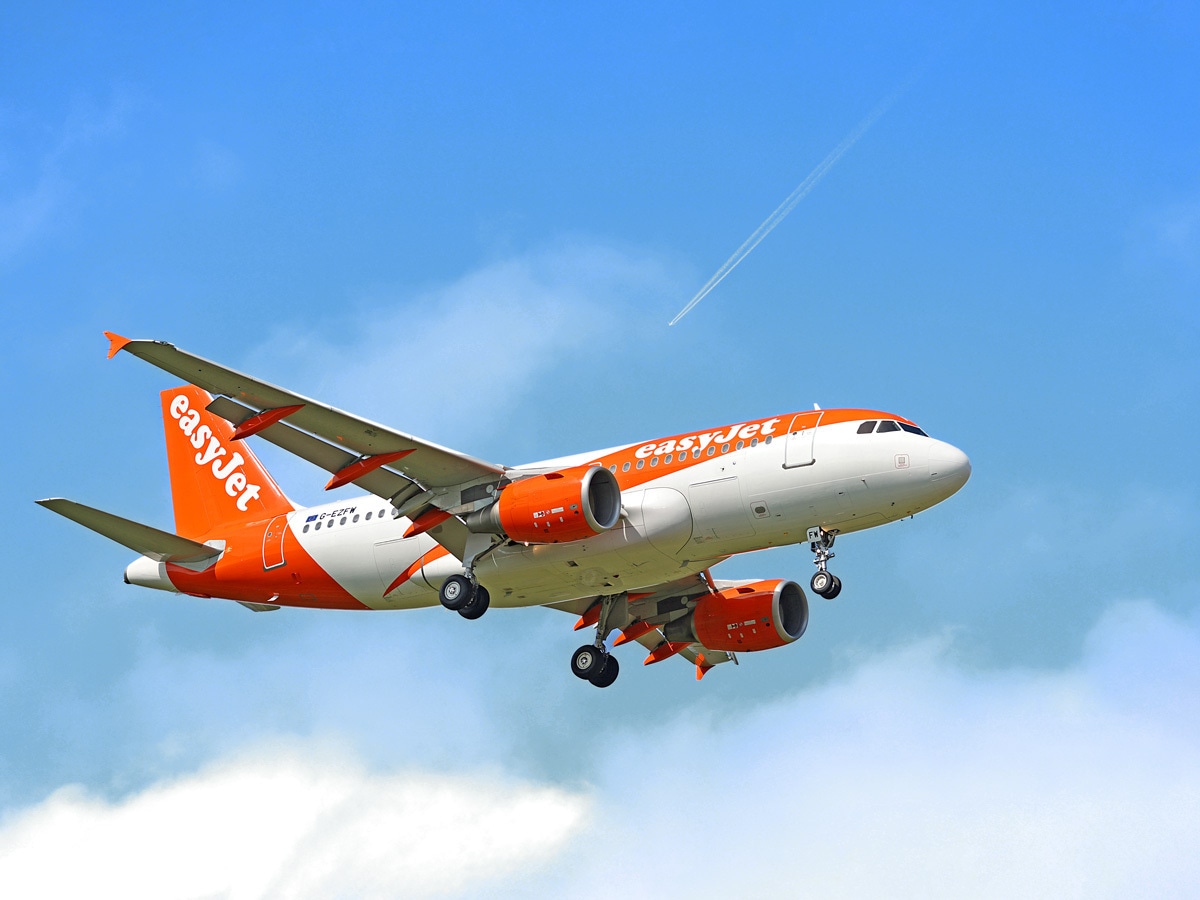 EasyJet share price: One of easyJet's distinctive orange and white planes flies under a blue sky.