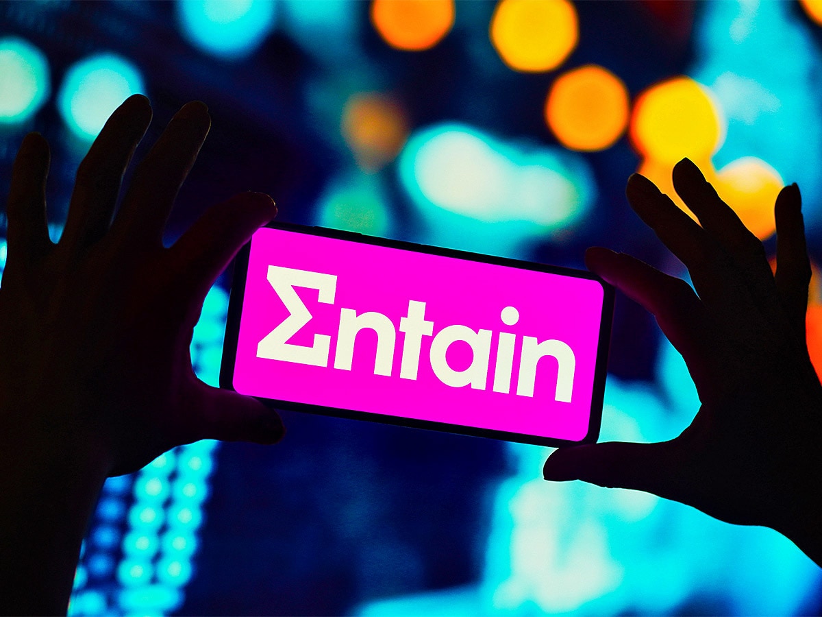 Person holding a mobile with an Entain logo