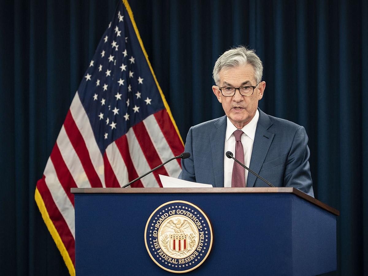 Fed chair Jay Powell stands at a lectern giving a speech in front of a US flag.