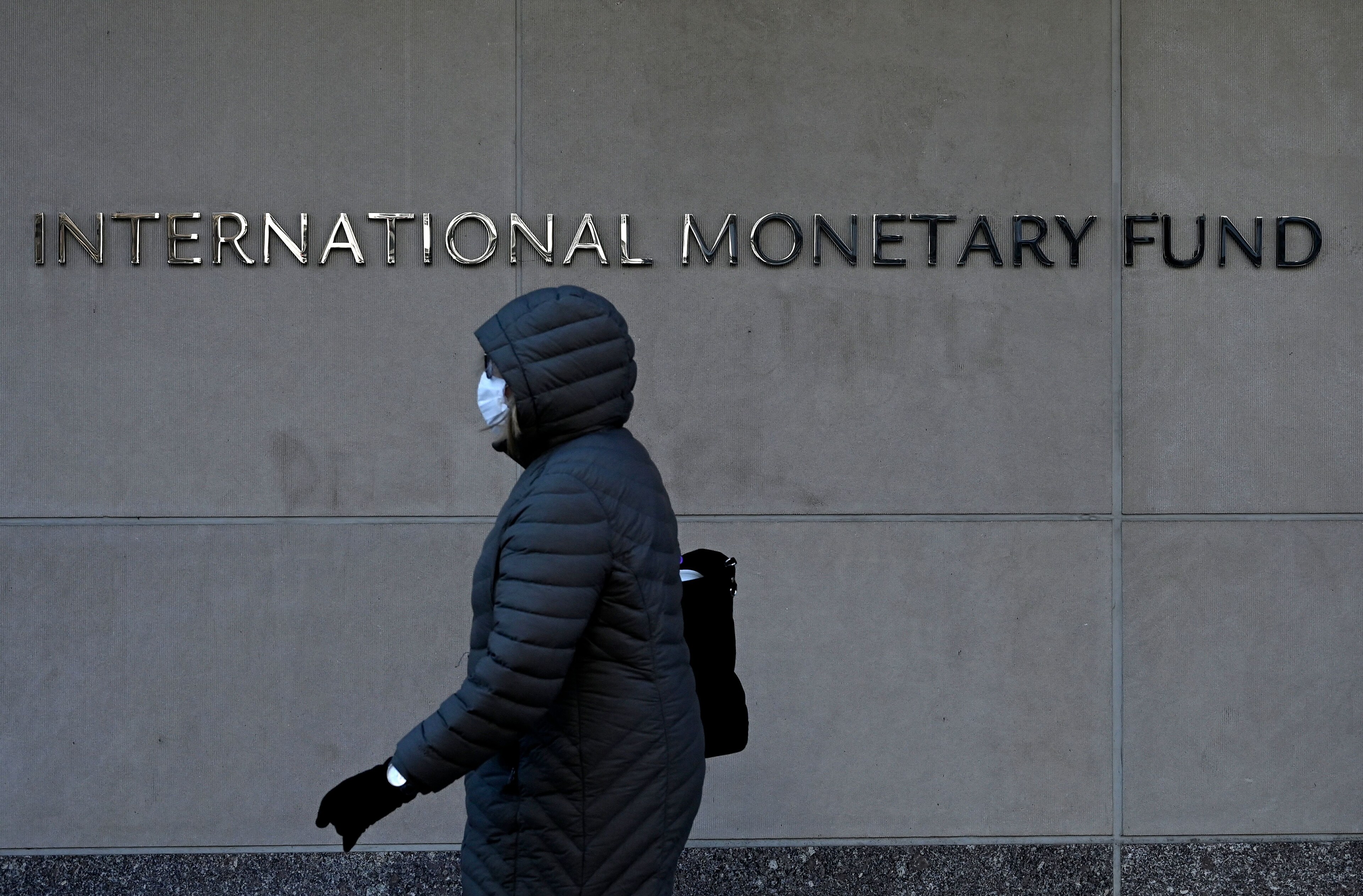 Person walking past IMF headquarters in New York