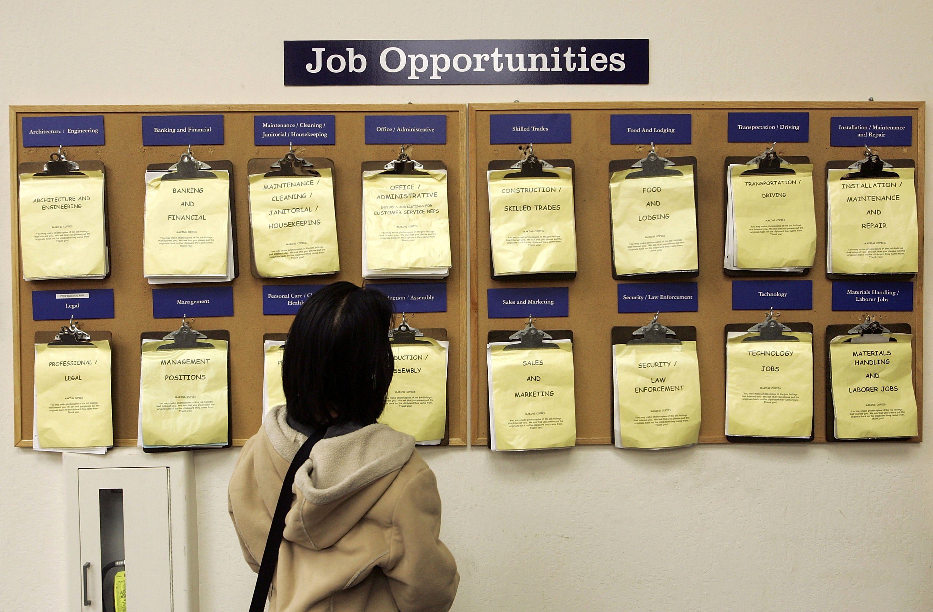 Image shows a jobseeker looking at a board of job vacancies.