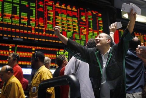 A happy trader holding his arms in the air on the trading floor