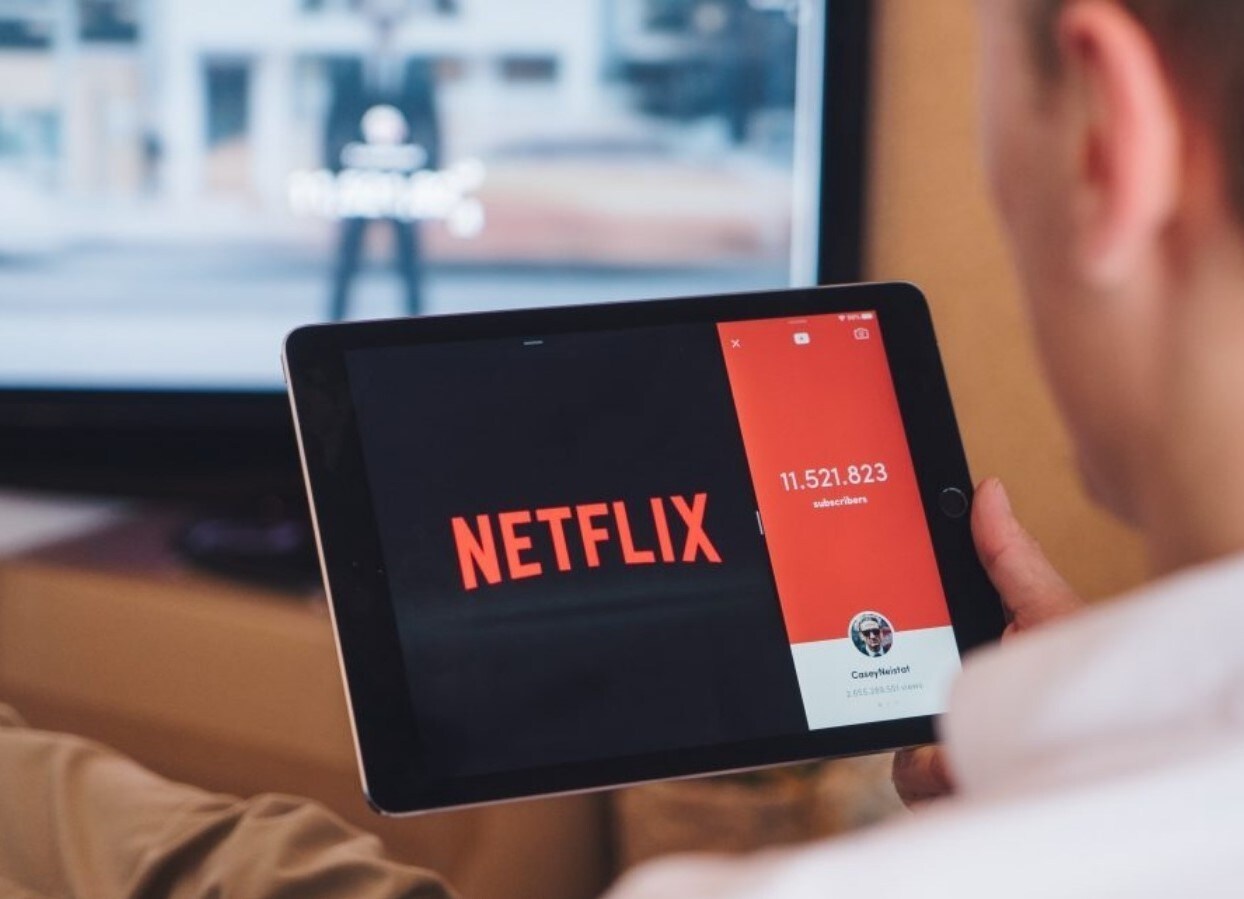 Netflix share price: a man watches Netflix on a tablet
