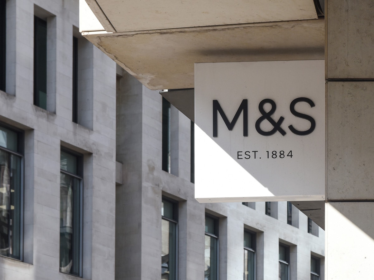 Marks & Spencer share price: the M&S logo hangs outside a shopfront.
