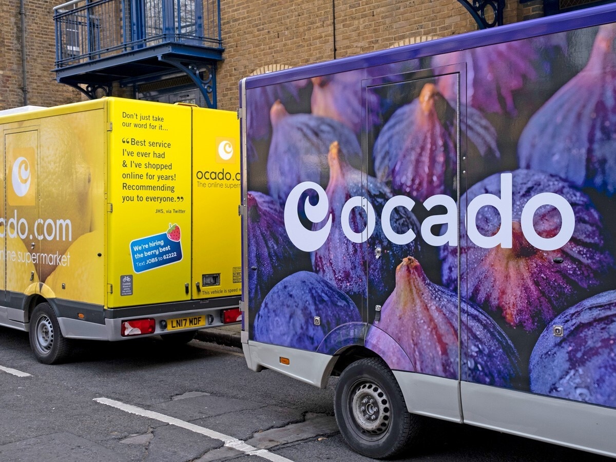 Ocado share price: Ocado delivery vans are parked outside a residential address.