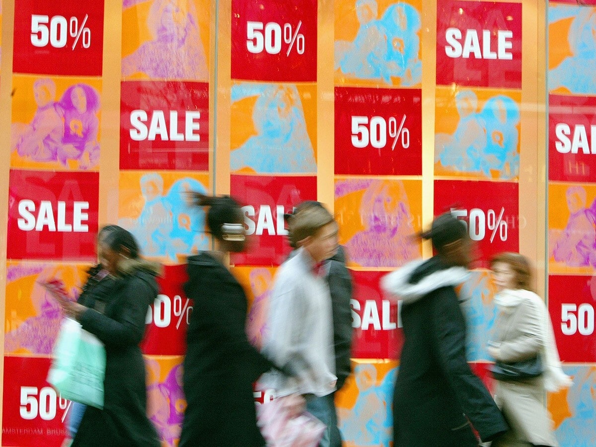 shoppers in front of sale signs at shops