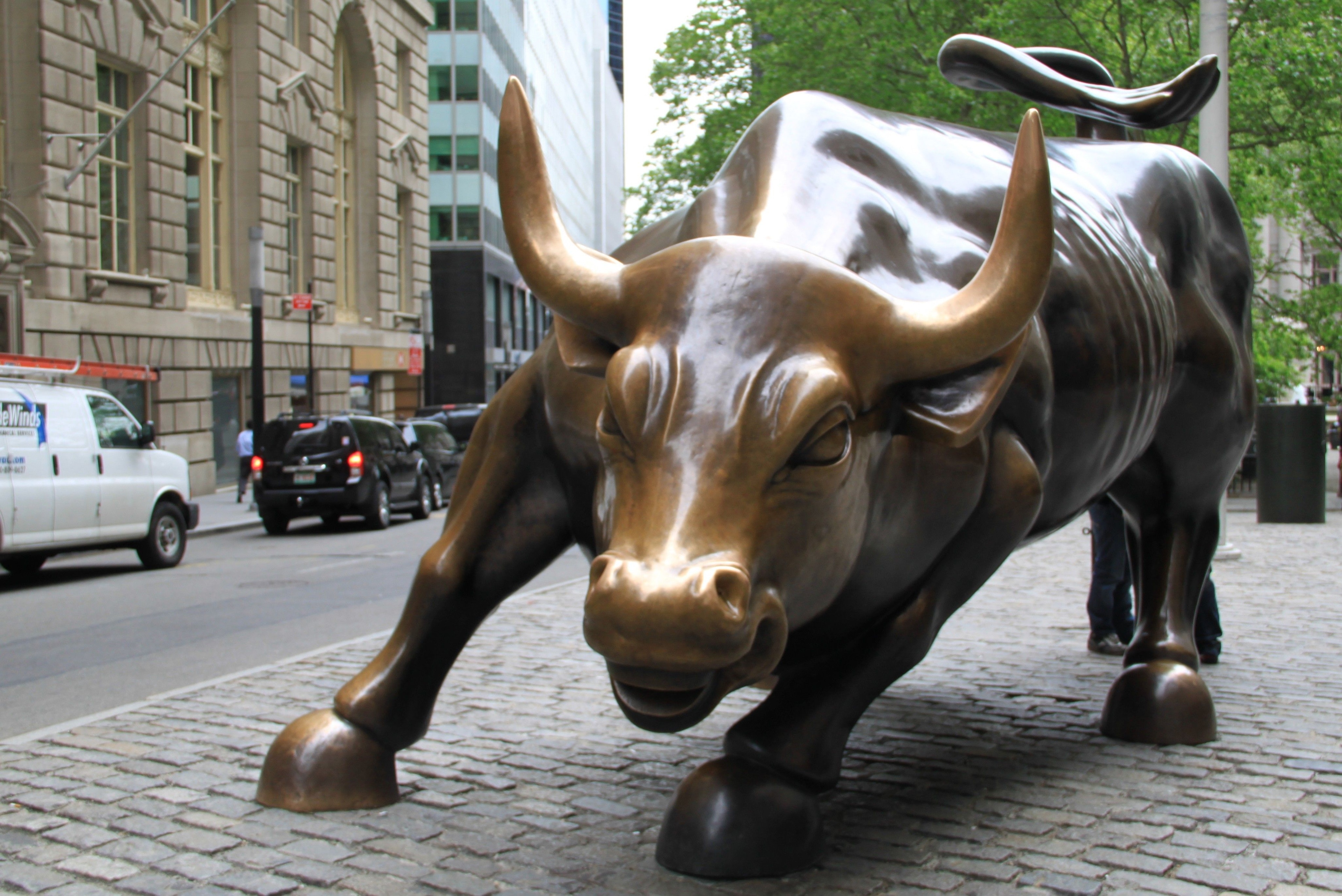 Image shows the famous bronze statue of a charging bull on Broadway in New York's financial district.