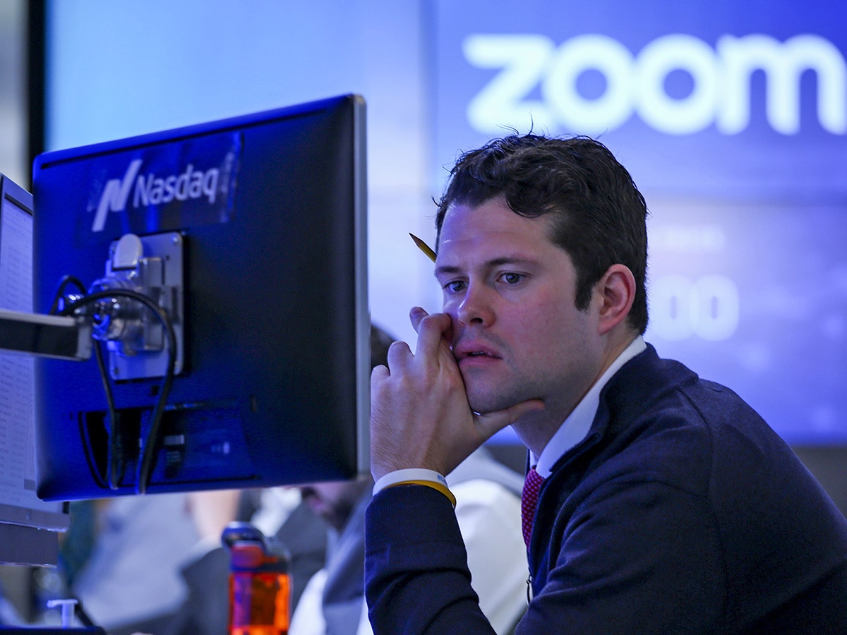 Trader working at the Nasdaq with a Zoom logo in the background