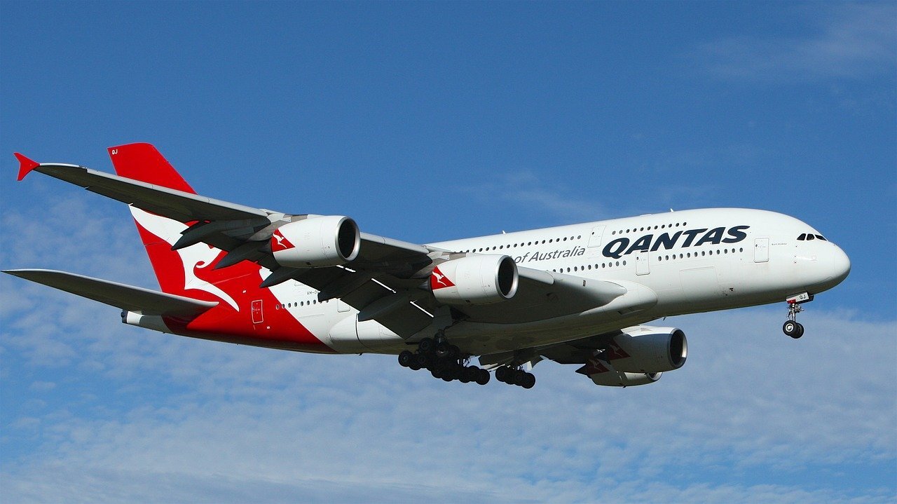 qantas jet flying in blue sky and clouds