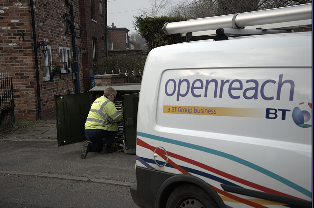 BT share price: a BT van is parked on a residential road as a worker connects broadband cables