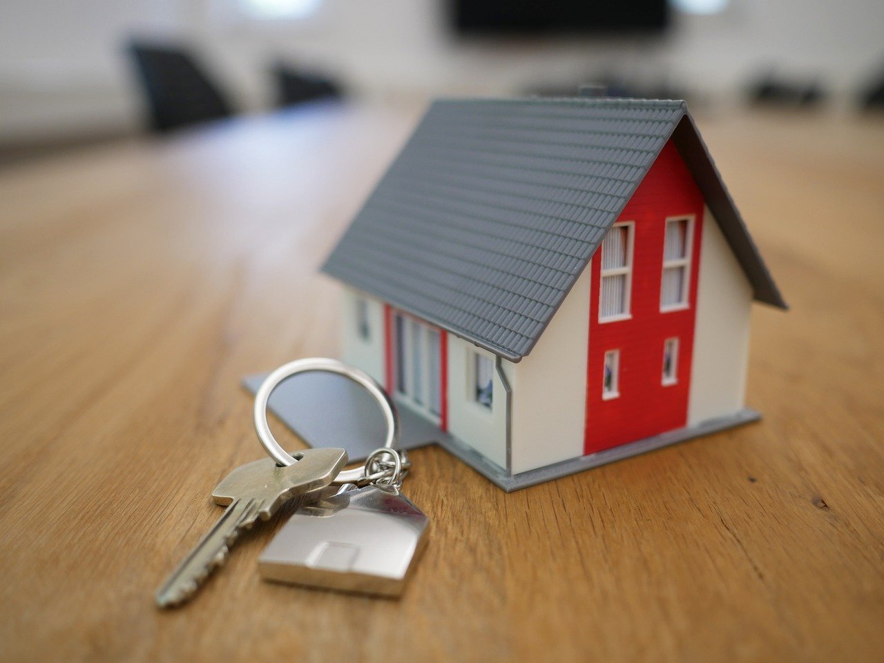 house key on a key ring in front of a tiny model house