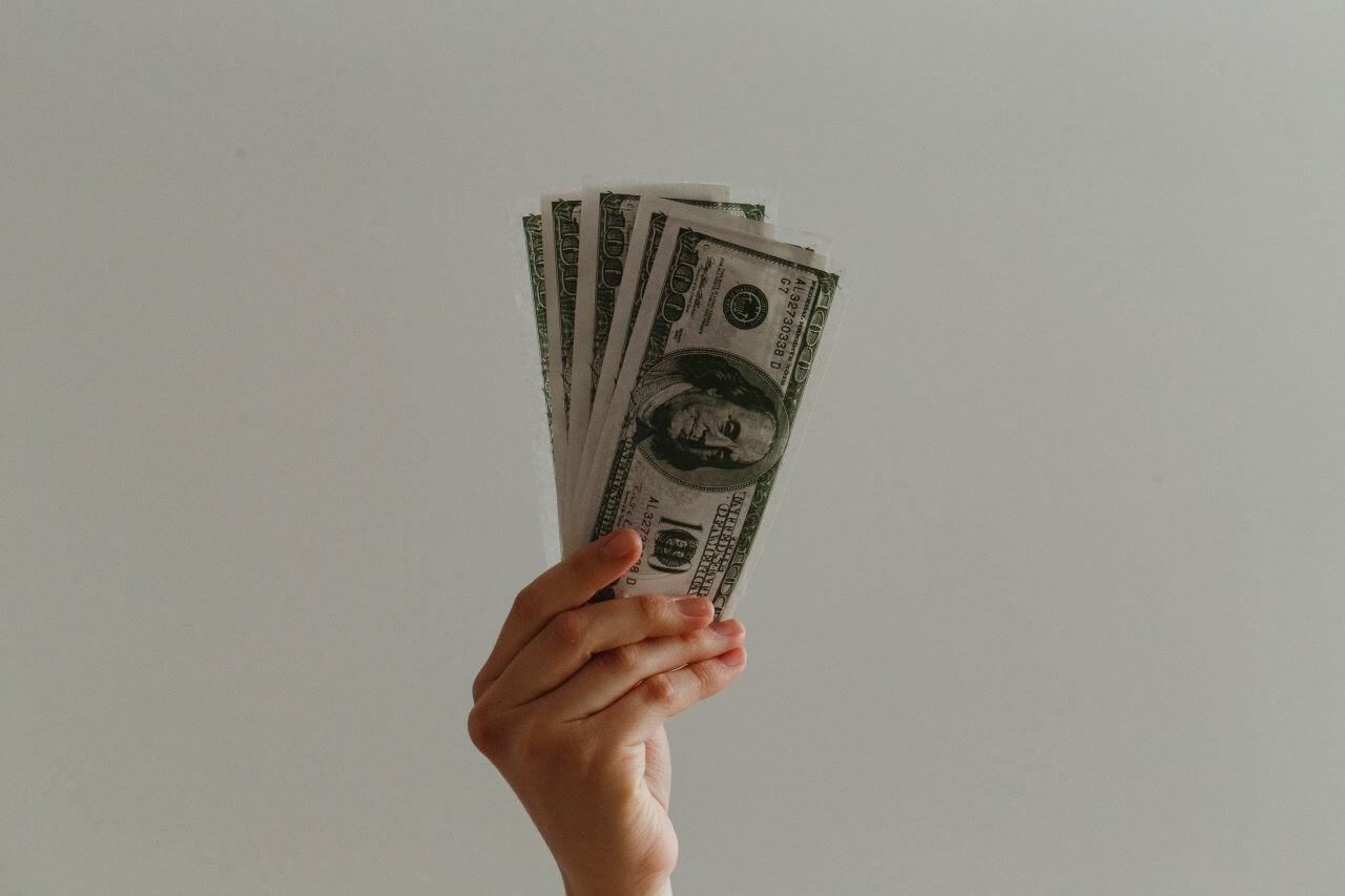 a hand holding a fan of money