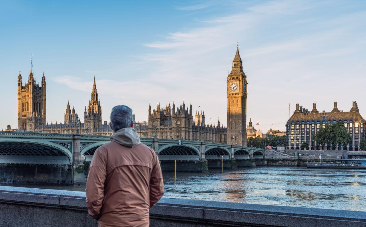 Mężczyzna patrzy na Big Bena i Most Westminsterski w Londynie o wschodzie słońca