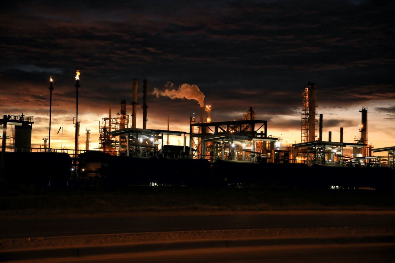 a factory at night with smoke coming out of the pipes