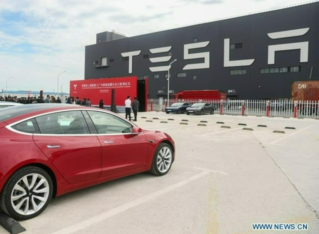 Tesla share price: a Tesla car is parked in front of a Tesla factory.