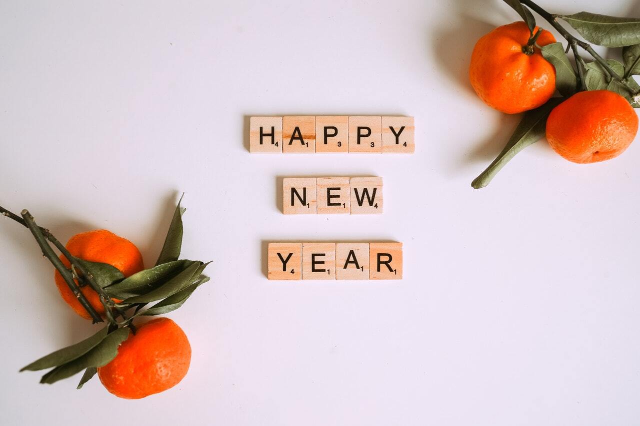 Happy New Year message in letter tiles with oranges in each corner to decorate