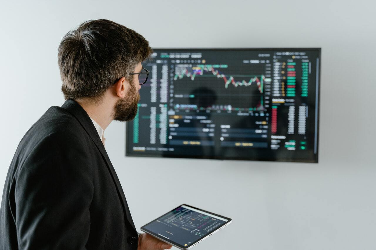 man looking at charts while trading on ipad