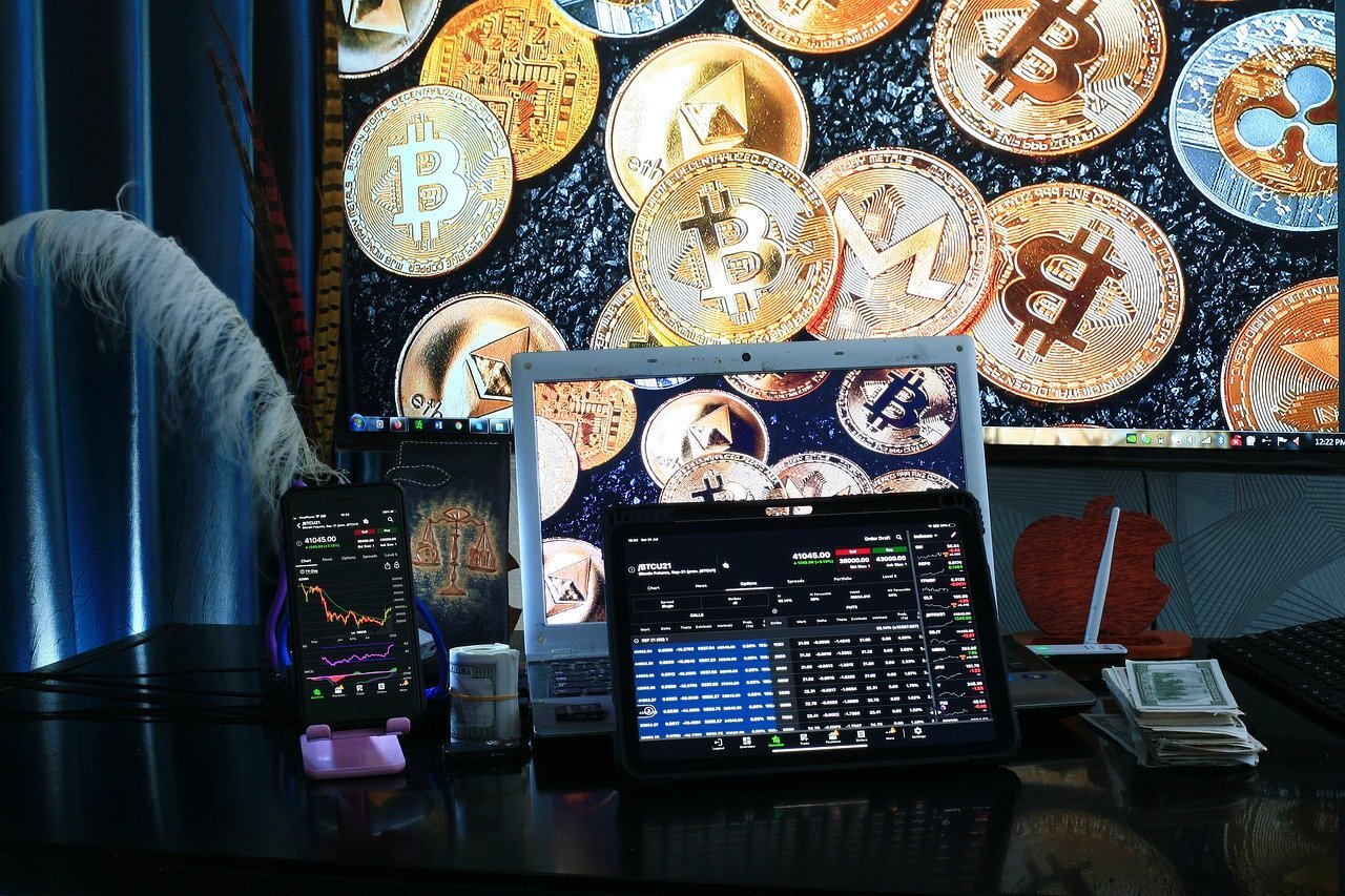bitcoin images behind computer with financial trading charts on the screen