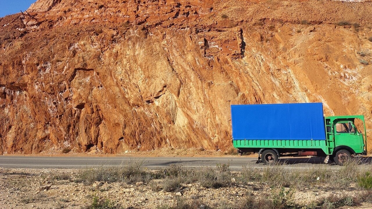 truck driving past red rock wall