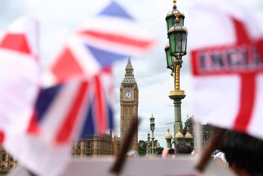 Flags are waved on Westminster Bridge, with the Palace of Westminster and Big Ben in the background.